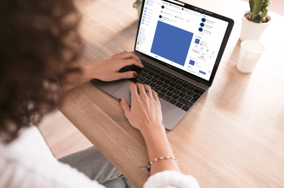 a woman using a laptop with a social media page on the screen