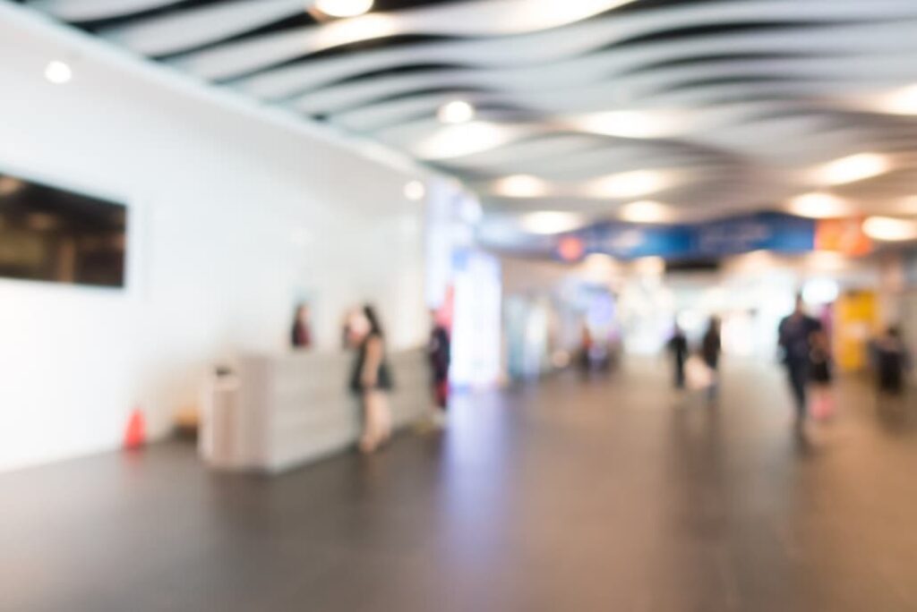 Blurred image of a busy exhibition hall with scattered attendees